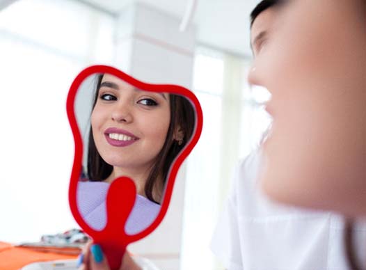 Woman with beautiful teeth smiling in mirror