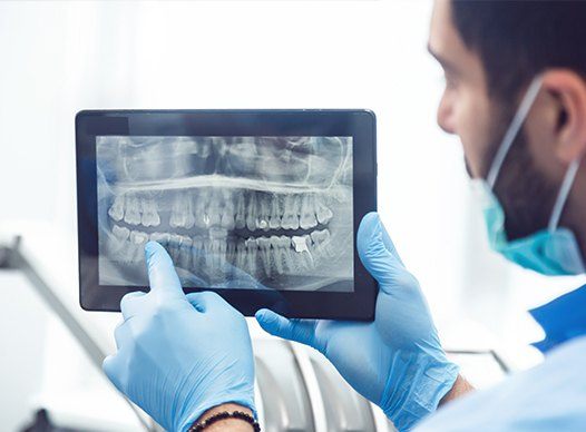 dentist pointing to x-ray on tablet