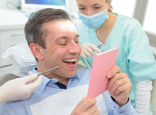 man checking smile in pink mirror