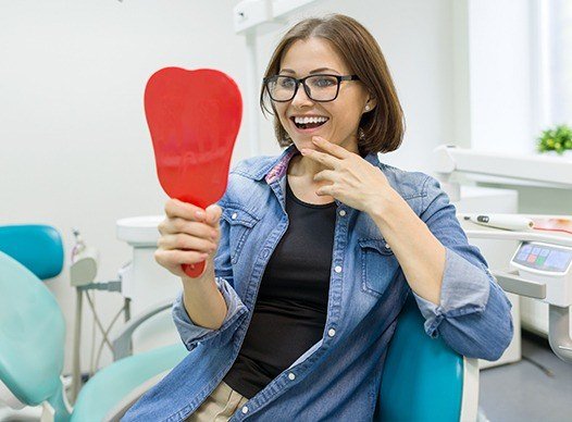 woman checking smile in red mirror happily