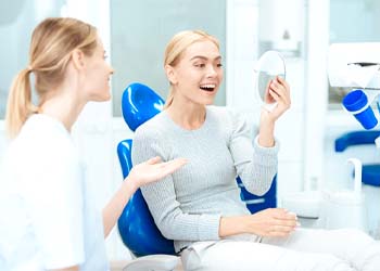 Patient smiling in mirror with cosmetic dentist in Moses Lake