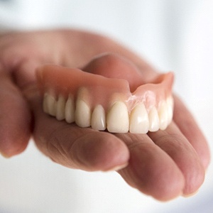 Hand holding upper full denture