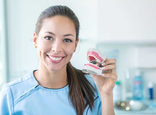 a person smiling and holding dentures
