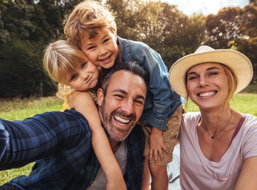 family of four sitting among trees and smiling 