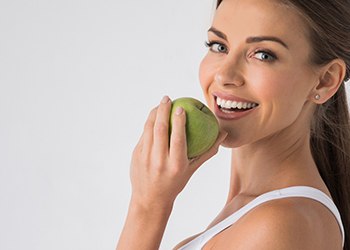 woman biting into a green apple 