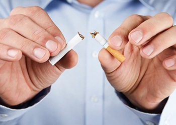 person breaking a cigarette in half 