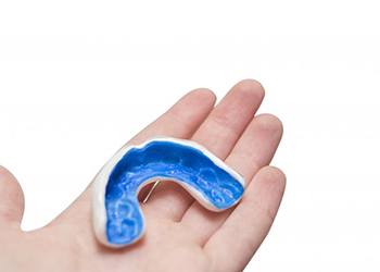 person holding a blue mouthguard in their hand 