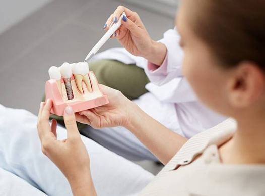 dentist showing a patient a model of a dental implant