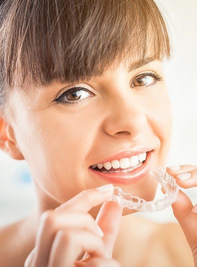 woman with bangs holding invisalign