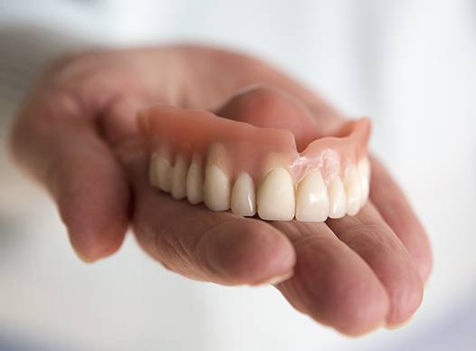 hand holding top dentures