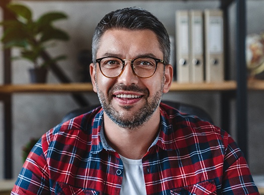 a person smiling and sitting in front of a bookshelf