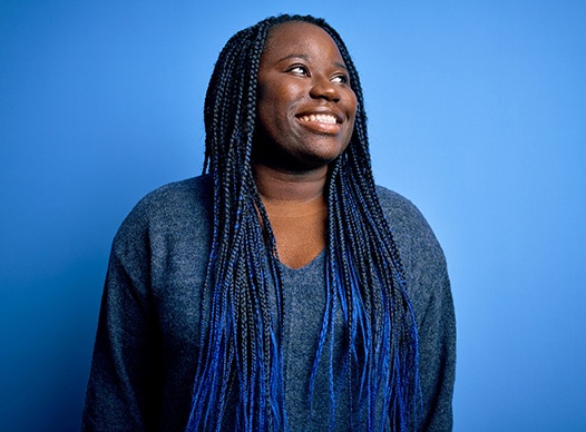 smiling person looking up and posing in front of a blue background