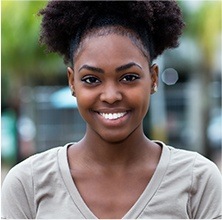 Young woman in gray blouse smiling outdoors