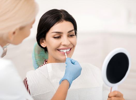 A dentist uses a shade guide to determine the correct color for a woman’s veneers in Moses Lake