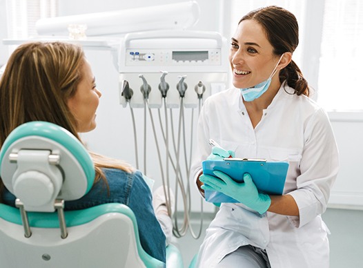 Dentist smiling at patient while taking notes on clipboard