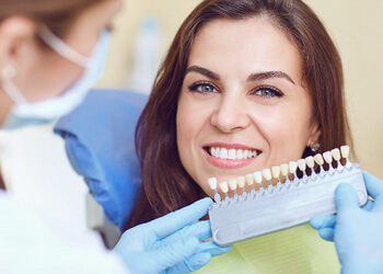 a dentist assessing the tooth color of her patient