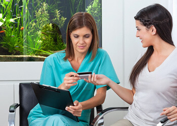 a woman paying the cost of teeth whitening