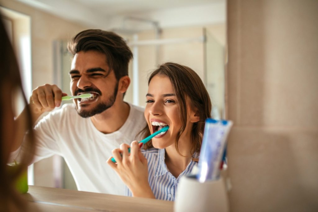 Man and woman brushing their teeth with tips from the dentist 