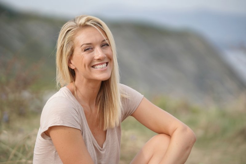 a young woman smiling and sitting outside after completing her full mouth reconstruction in Moses Lake