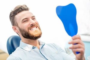 Man looking in mirror at cosmetic dentist