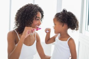 a mother and child brushing their teeth together