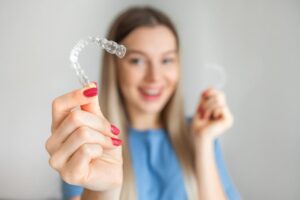 Young woman holding clear aligner.