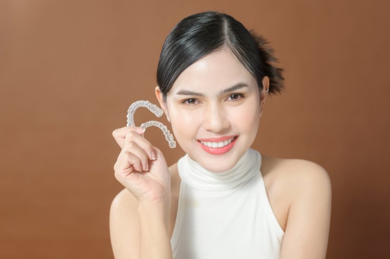 Lady smiles holding clear aligners