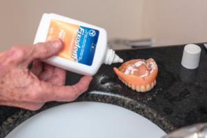 a person applying denture adhesive to the roof of their denture